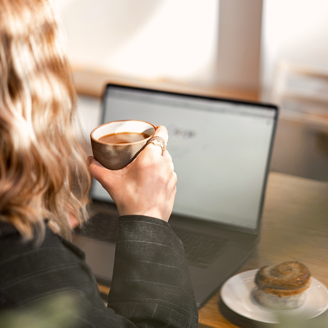 woman drinking coffee whilst using computer