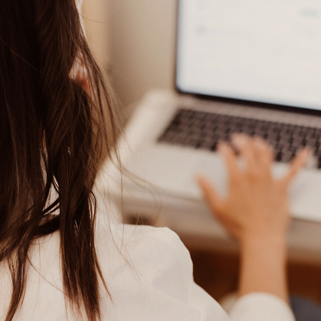 Woman With Brown Hair Typing On Laptop Wearing White Blouse